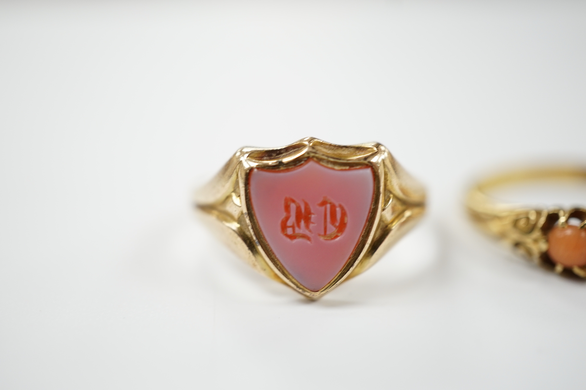 An early 20th century 18ct and graduated five stone split coral bead set half hoop ring, size O and a Victorian 12ct gold and sardonyx set shield shaped signet ring, size Q.